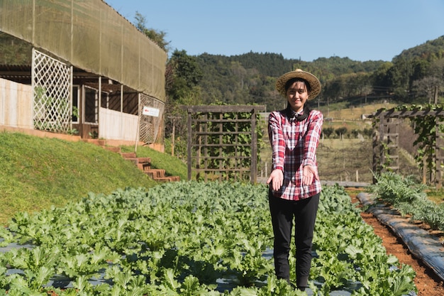 Foto contadino intelligente e concetto di prodotti vegetali; giardiniere femminile che controlla di recente le piante in azienda agricola