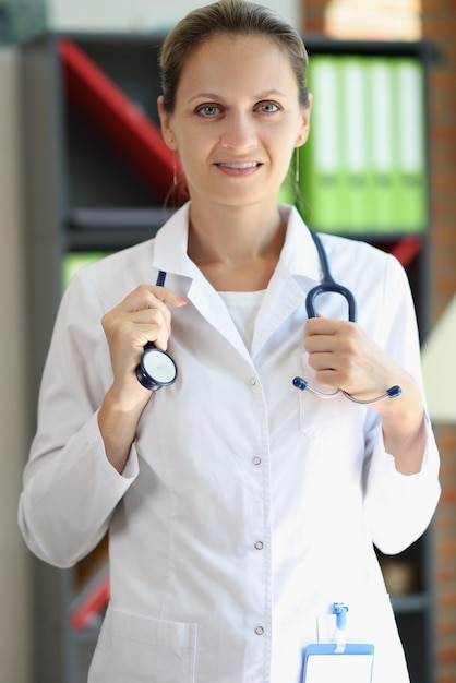 Smart female doctor holding stethoscope and looking at camera