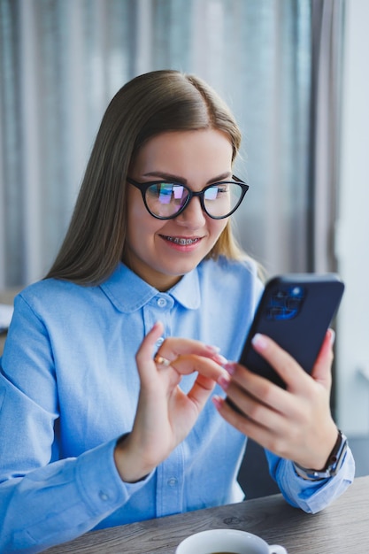 Smart female employee with netbook looking at camera during mobile call successful freelancer in jacket talking on phone via app