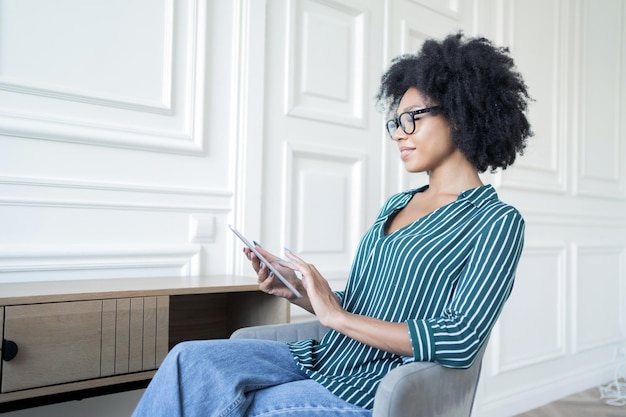 안경을 쓴 스마트한 프리랜서 여성은 태블릿을 사용하여 비즈니스에서 온라인으로 보고서를 작성합니다.