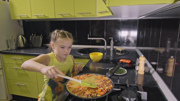 Smart girl learning to cook Young mistress children to cook a Neapolitan egg fried omelette