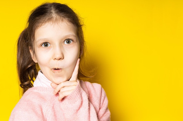 Smart girl. Smart child on a yellow background, the child has an idea.