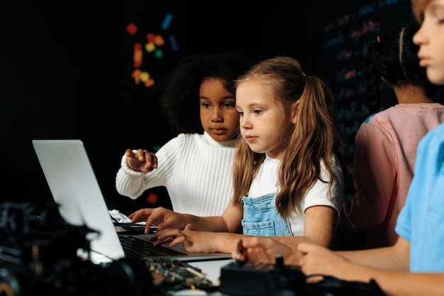 Photo smart girl in white bib learning robotics technology using laptop erudition