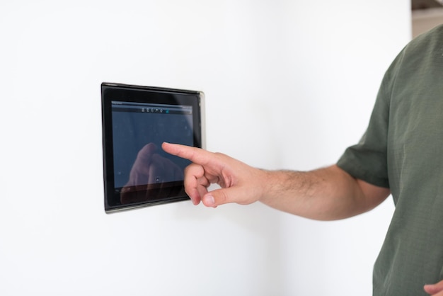 smart home en technologie concept close-up van mannelijke handen wijzende vinger naar tablet pc-computer geïntegreerd in de binnenmuur van het huis