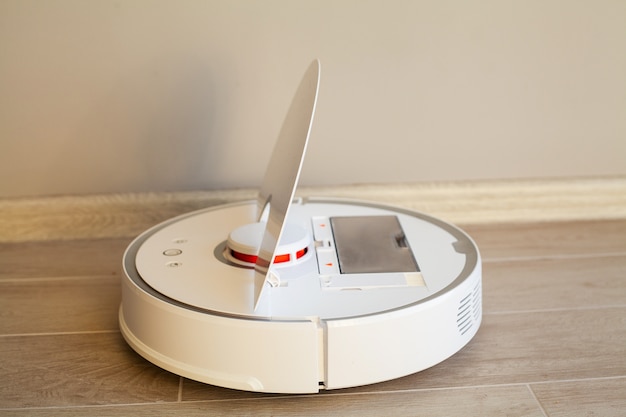 Фото Умный дом. пылесос-робот работает на деревянном полу в гостиной