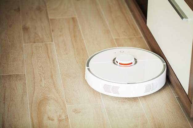 Smart house, robot aspirapolvere gira sul pavimento di legno in un salotto,