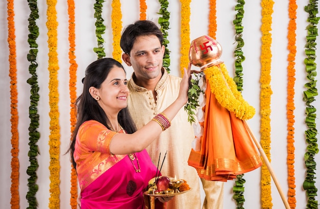 Smart indian young couple performing gudi padwa puja in traditional cloths & pooja thali. it's a hindu new year celebrated across india