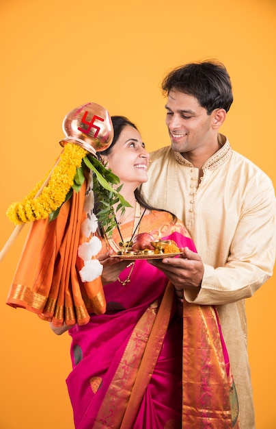 Smart Indian young couple performing Gudi Padwa Puja in traditional cloths & pooja thali. It's a Hindu New Year celebrated across India