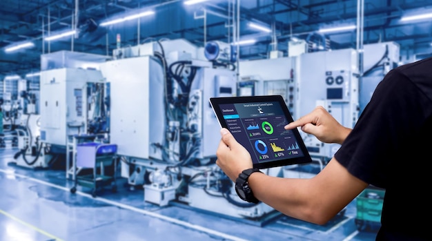 Smart industry control conceptHands holding tablet on blurred automation machine as background