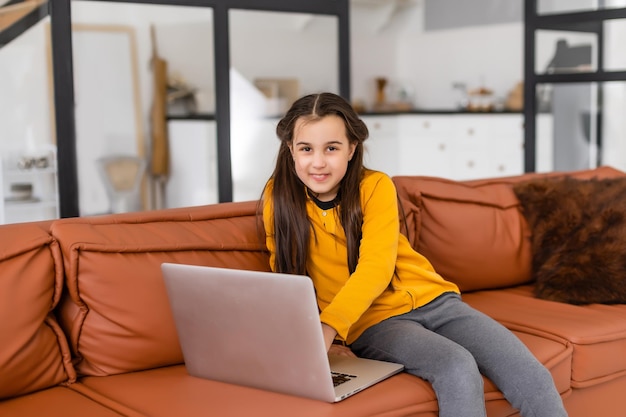 Smart Little Girl Does Homework in Her Living Room. She's Sitting and Uses Laptop.