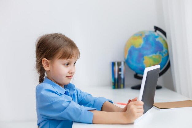 Умная маленькая школьница с цифровым планшетом в классе. Ребенок в начальной школе. Образование и обучение для детей.