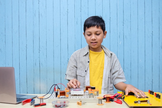 Smart looking Asian boy working with circuits, wires, computer, motor on his project. Science, Techn