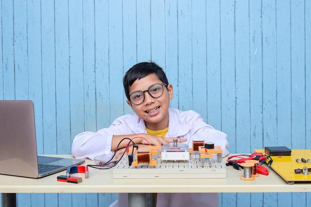 그의 프로젝트에서 회로, 전선, 컴퓨터, 모터와 함께 일하는 똑똑해 보이는 아시아 소년. 과학, 기술