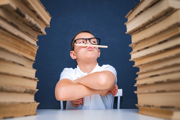 Smart looking boy holding pencil in his mouth, looking away and thinking