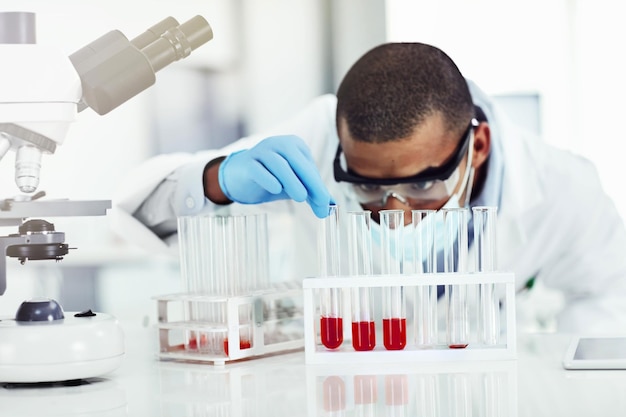 실험실에서 혈액 샘플 DNA 테스트 또는 바이러스 연구와 함께 일하는 똑똑한 과학자 흑인 남성 과학 또는 생물학 전문가는 실험실에서 질병 또는 의료 혁신을 위해 시험관을 분석