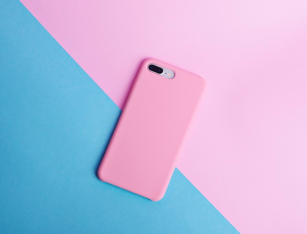 スマートフォンの背面図ピンクの電話ケースのモックアップピンクと青の背景に分離