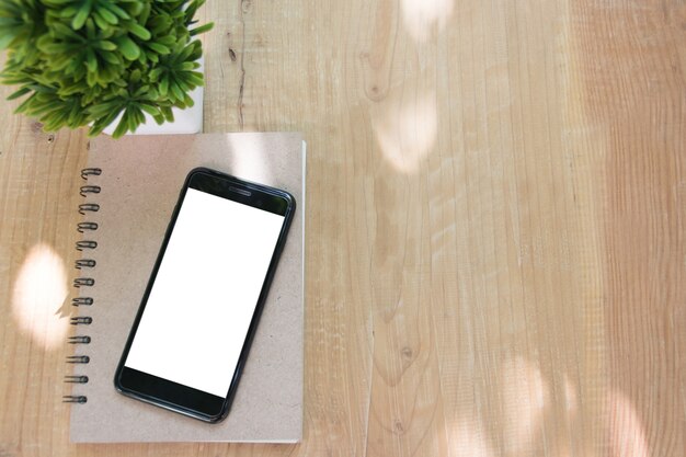 Smart phone over book on wooden table of brown