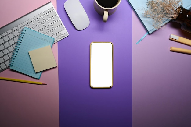 Smart phone, coffee cup and stationery on purple background.