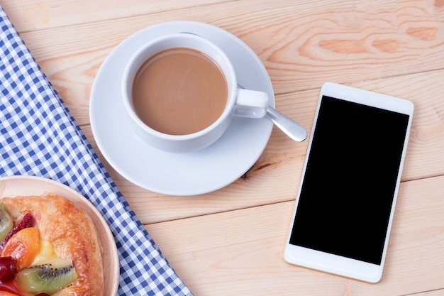 smart phone and cup of coffee on wooden background.