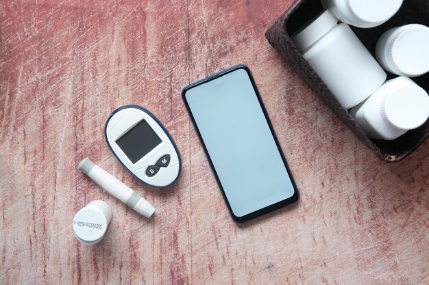 smart phone and diabetic measurement tools and pills on table