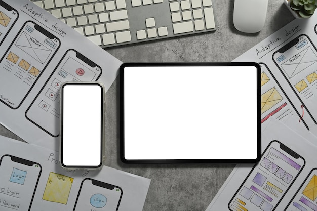 Smart phone and digital tablet with wireframe sketches of screens for mobile application on office desk