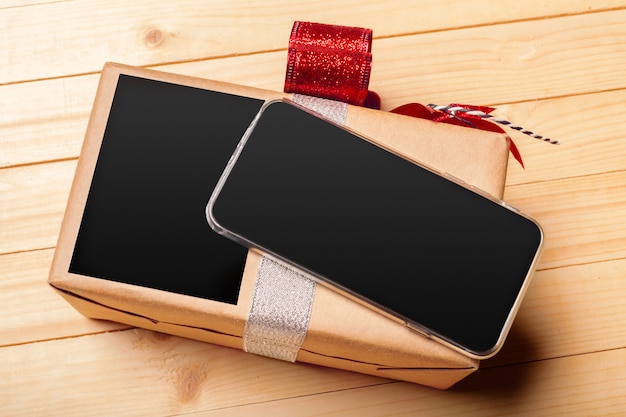 Smart phone and gift on wooden background