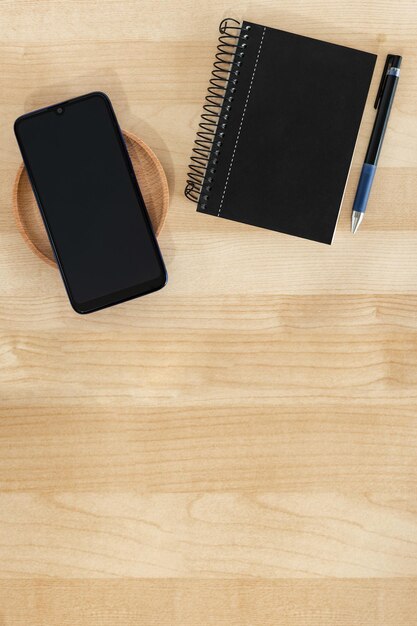 Smart phone notebook and pen in black color on wood background Office banner style