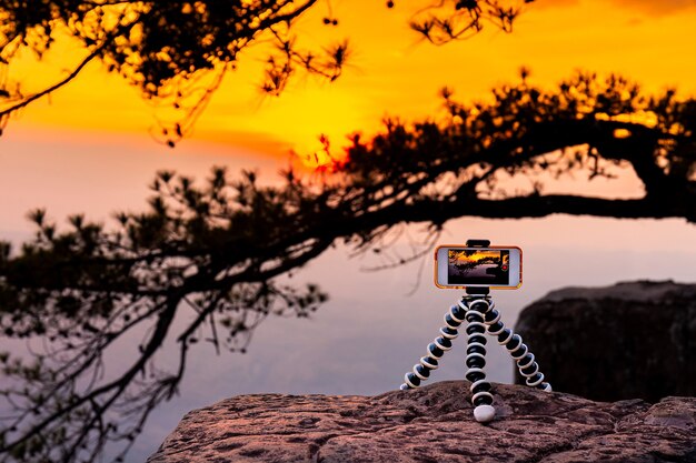 Smart phone take photo on tripod with nature sunset view on high mountain during travel