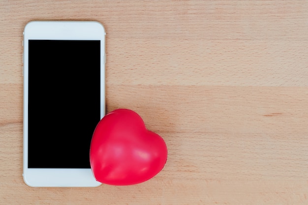 смартфон с красным сердцем символ на деревянный, используя в качестве фона