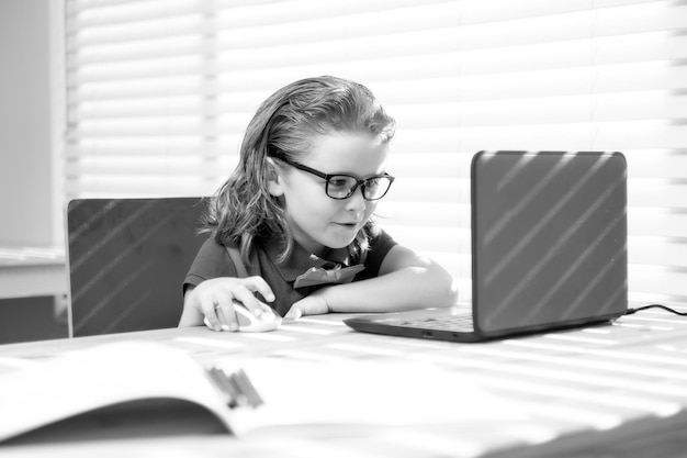 Умный школьник пишет домашнее задание, используя ноутбук для учебы маленький школьник учится онлайн