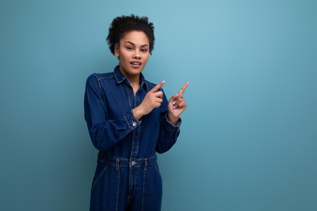 Smart slim young hispanic brunette woman with fluffy curly hair in a blue denim suit is actively