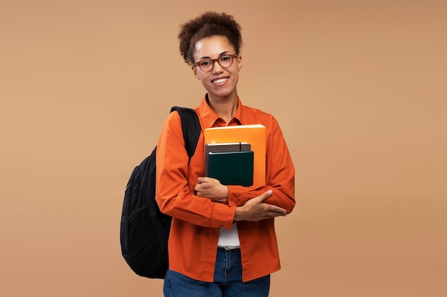 Smart smiling African American student in eyeglasses holding books isolated on background. Education