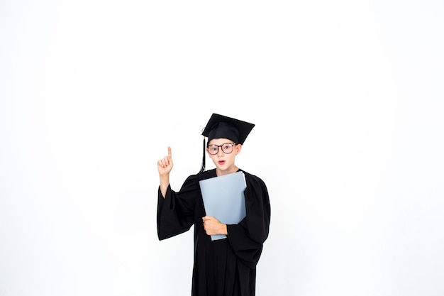 A smart student in an academic hat and glasses stands with books