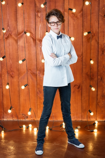 Smart teenager wearing glasses posing in loft apartment teenage\
girl in white shirt on light bulbs b...