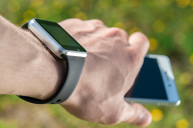 Smart watch on the hand that holds the phone.