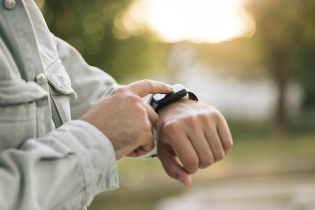 Smart watch on a mans hand outdoor mans hand touching a smartwatch close up shot of males hand uses