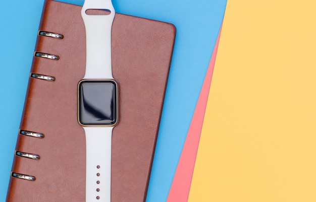 Foto smart watch su notebook per organizzare il concetto con il giallo blu rosa