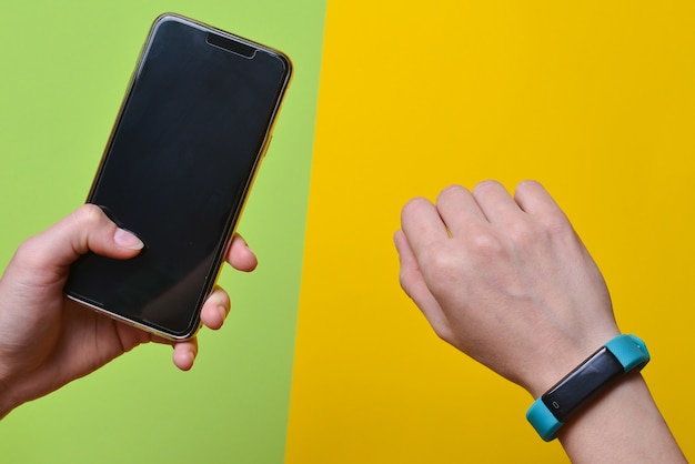 Smart watch on the wrist and a smartphone in the hand synchronization. Fitness bracelet Modern technologies.
