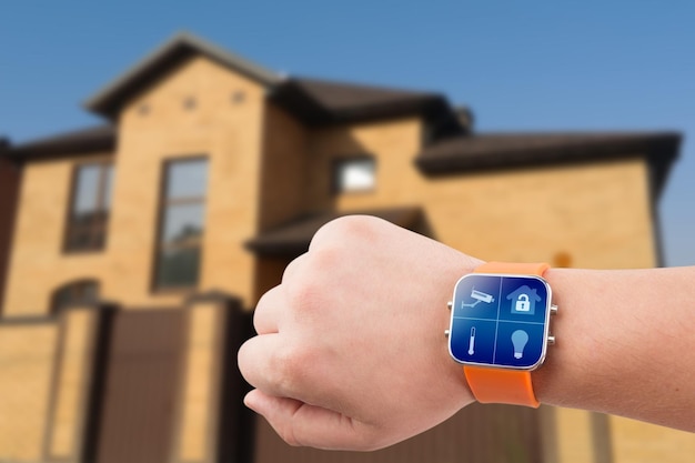 Smart watches with home security app on a hand on the building background