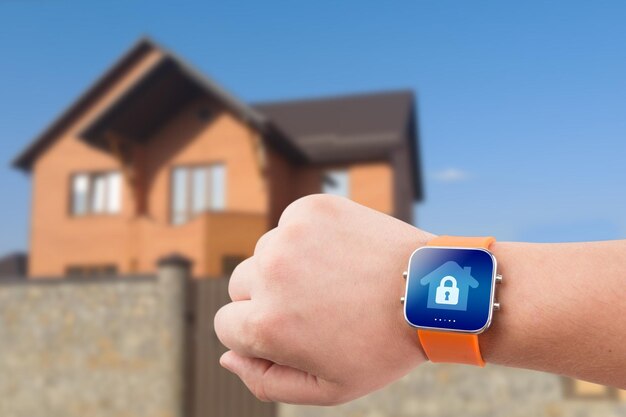 Smart watches with home security app on a hand on the building background