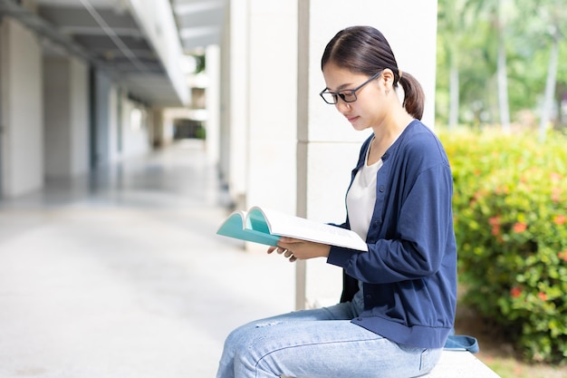 Умная женщина, сидящая и читающая книгу, использует свободное время для обучения книжному червю в университете