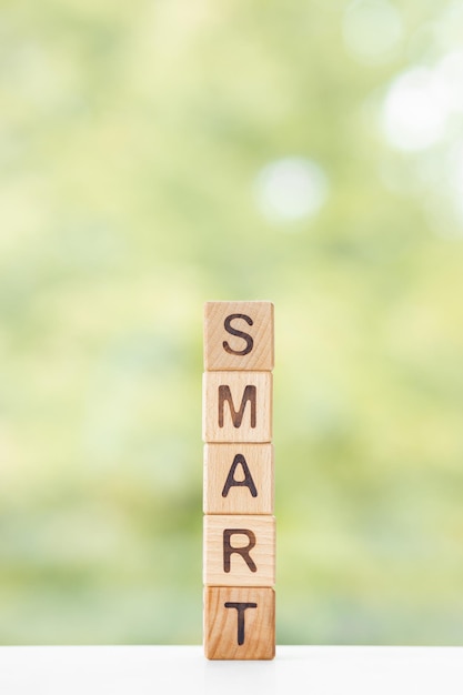 Smart word is written on wooden cubes on a green summer background Closeup of wooden elements