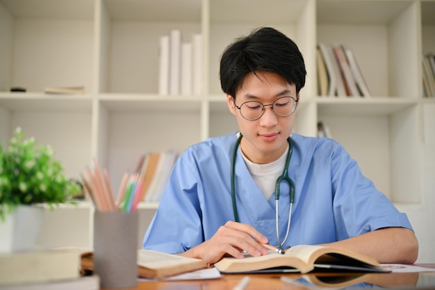 Smart young Asian male medical student reading a book preparing for exam