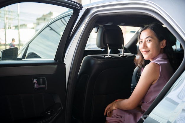 Smart young and beautiful asian businesswoman getting in or\
getting out of a car, business travel in modern - urban lifestyle.\
business woman travel in the city by private taxi.