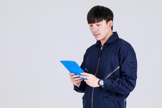 Smart young chinese guy on service uniform jacket recording creative idea by writing memo on note board and consider future design and vision by thinking about strategy to aim target as planning.