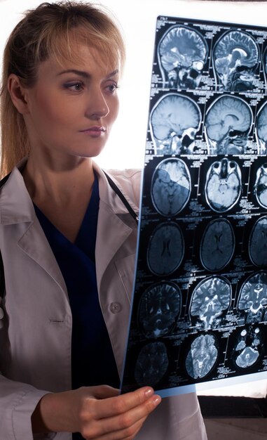 Smart young doctor woman in white labcoat looking through mri of human brain