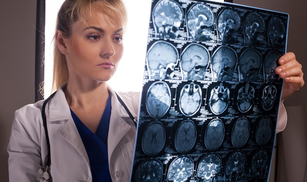 smart young doctor woman in white labcoat looking through mri of human brain