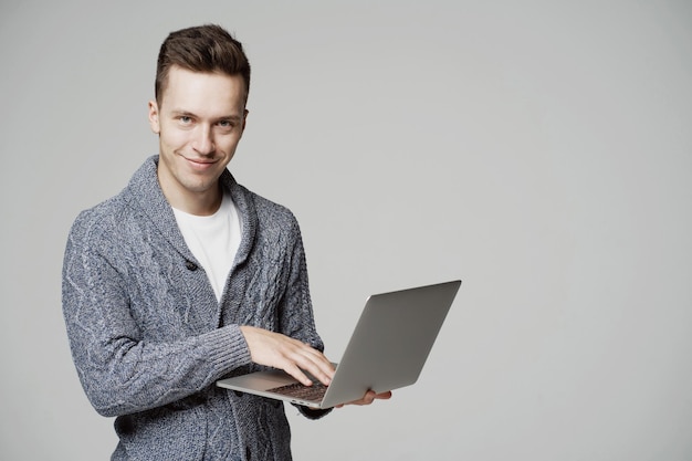 smart young man student of european appearance working on a laptop and looking at the camera