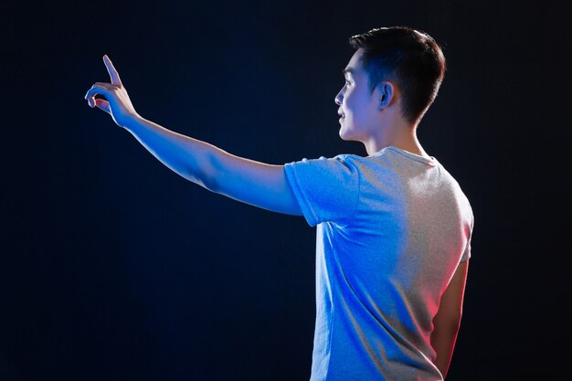 Smart young man using the sensory screen while standing against black background