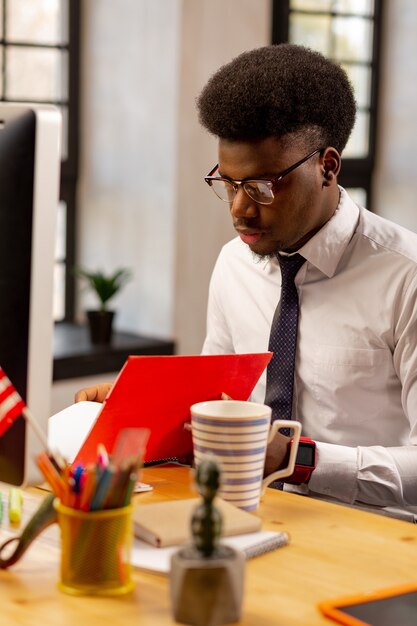  Smart young office worker looking at the documents while doing his job